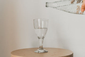 glass bottle pouring water over glass on wooden chair
