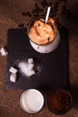 Iced korean Dalgona Coffee, a trendy fluffy creamy whipped coffee with a white tube and ice. trendy coffee drink