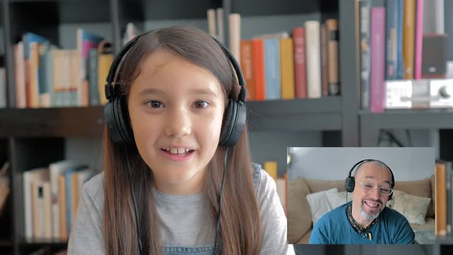 Ni&ntilde;a peque&ntilde;a conversa con auriculares en videoconferencia muy feliz y mandando besos con su padre