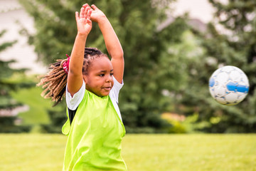 Obraz premium A young African American girl is learning how to play soccer on a sunny day 