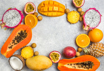 Set of exotic tropical fruits on light gray background - papaya, mango, pineapple, dragon fruit, orange, coconut, passion fruit, longan. Top view