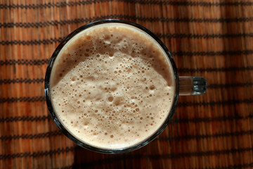 Glass beer mug filled to the brim with beer with foam, top view