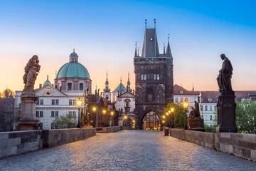 Papier Peint photo autocollant Pont Charles Lampes qui brillent sur le pont Charles en pierre médiévale avec des statues de saints pendant le crépuscule, Prague, République Tchèque