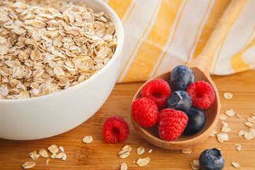 Bowl of muesli, raspberry and blueberries for healthy breakfast. Tasty breakfast with oatmeal and natural berries and pastel background.