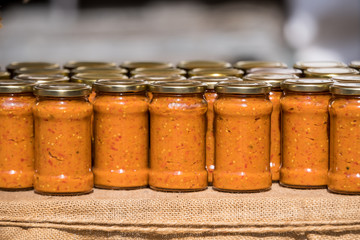 Many jars with zacusa, a Romanian traditional food prepared with boiled vegetables as tomattoes, onions and eggplants, displayed for sale at a street food market

