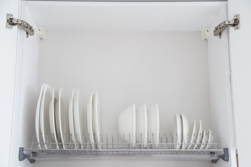 Dish drying metal rack with big nice white clean kitchenware. Traditional wall cabinet kitchen