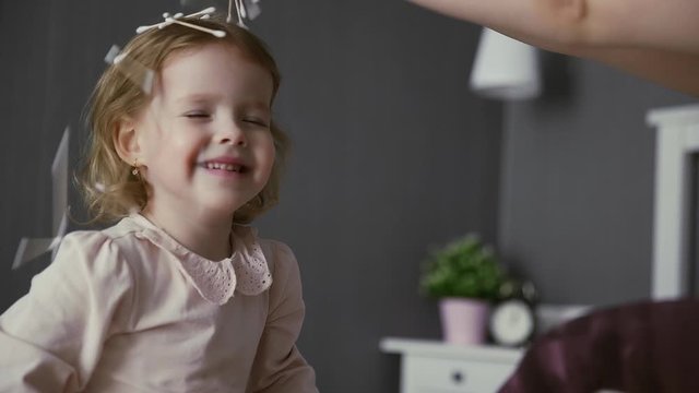 Active young mom babysiter and cute little kid daughter playing in bedroom. Happy litte girl plays with cotton swabs