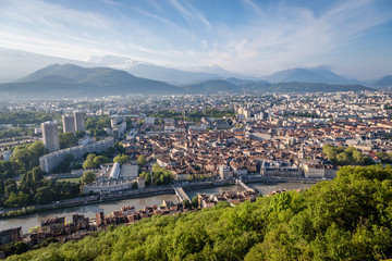 Fototapeta na wymiar Iconic new buildings in Grenoble France on the left with the french alps in the background and the Isere river and trees in the foreground