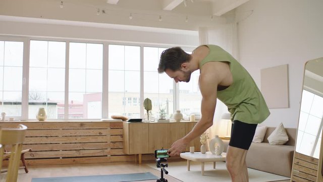 Fit Caucasian male recording a blog or streaming yoga workout from home. Stay home, quarantine life. Shot on ARRI Alexa Mini with Cooke S4 lens