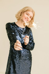Celebration, fun and holidays concept - happy young woman in sequin dress with sparklers at party
