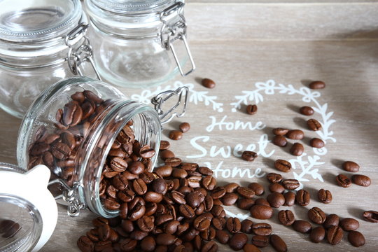 Food storage - tree small glass jars with scattered coffee arabica beans on gray tray