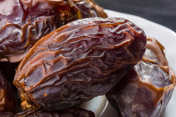 Big luxury dried date fruit in bowls on the dark surface, kurma ramadan kareem concept, close up.