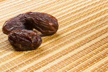 Big luxury dried date fruit on the bamboo mat, kurma ramadan kareem concept, close up.