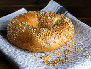 Fresh homemade pastries - bagel with sesame seeds on a linen napkin. Delicious breakfast.