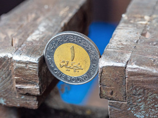 Dirham coin clamped in a metal vise. Currency and United Arab Emirates economy under the onslaught, the concept of financial problems and crisis