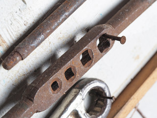 an old rusty tap wrench on a gray wall close up