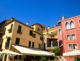 Fototapeta na wymiar Colored houses with canopies against the blue sky in Venice. Italy