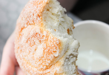 A bitten-off Sweet bun sprinkled with sugar in the hands.