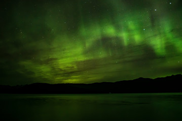 Aurora borealis over water and mountains