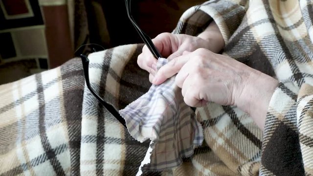Old female hands and glasses on a blanket