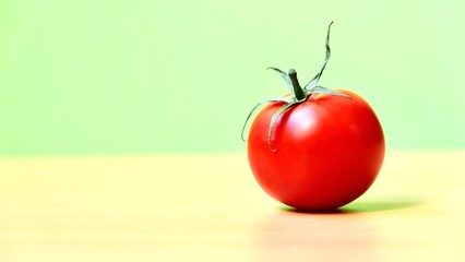 Ripe red tomato on a light green background 