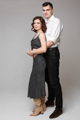 Studio portrait of an affectionate loving husband kissing his wife with eyes closed and smiling in her forehead. Couple snuggling close on black background. Love concept.
