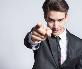 Young businessman pointing finger at camera 