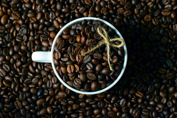 white Cup with coffee beans on the background of coffee beans