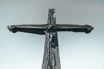 czarno białe zdjęcie starego, drewnianego krzyża z figurami Jezusa Chrystusa na tle nieba