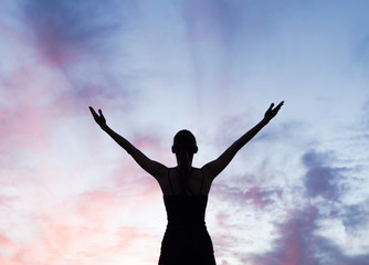 Fototapeta na wymiar Young woman with arms up to sunset sky feeling happy, energized and rejuvenated. 