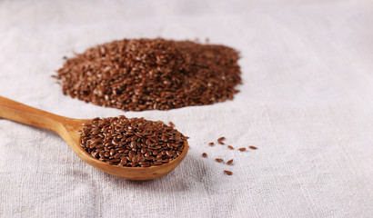 Flax seeds in a wooden spoon on a natural linen tablecloth, Copy space, Horizontal format