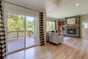 Living room with stone fireplace and light hardwood floor and sliding door to the back yard.