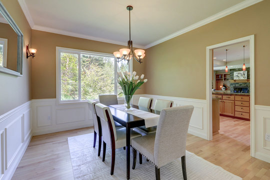 Classic elegant mustard color and grey tones dining room with large table and linen chairs.