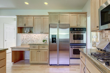 Classic cozy bright kitchen interior with wooden cabinets and granite grey green countertops.