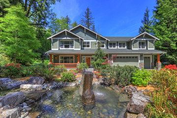 Beautiful long two story tall Northwest Home Exterior in grey green with spring landscaping and large driveway, garden and grass fresh lawn.