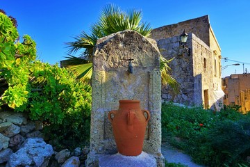 Old house with an old water tap and very old jug at the walking route