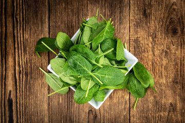 Portion of fresh Spinach on a wooden table (close-up shot)