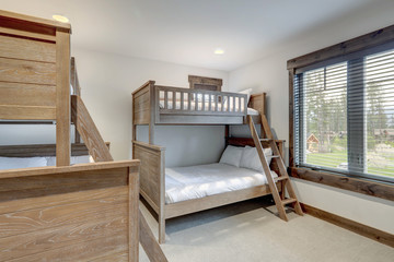 Natural tone bunk bed kids  bedroom interiors in new American vacation home. Wood furniture and...