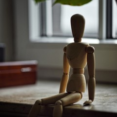 wooden mannequin sitting on a window