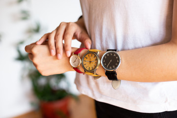 close up photo of female hands wearing three different hand watches  with different numerals. Black, yellow and read wrist watch. 