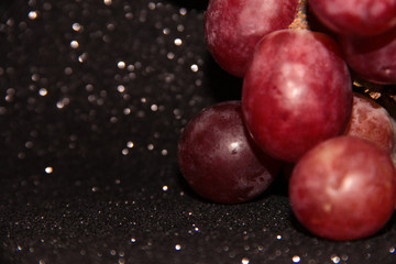 Large pink grapes on a black shiny background.