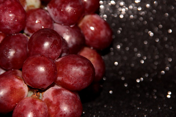 Clusters of grapes on a black shiny background.