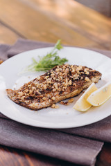 Big roasted carp steak with lemon and rosemary on plate