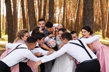 Happy wedding, group of bridesmaids, groomsmen, bride and groom having fun and embracing after...