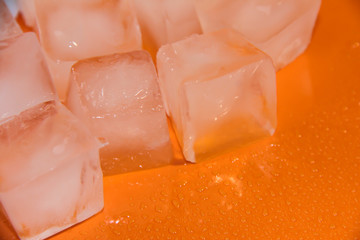 Chunks of ice on an orange background. Ice on a bright background.