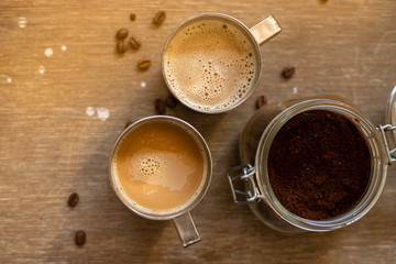 Coffee with milk in metal cups on a wooden table, top view