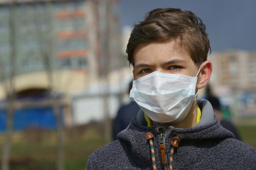 teen in a medical mask on the street in the city