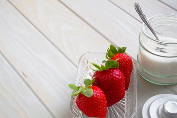 delicious red strawberries next to bowl with sugar and a spoon