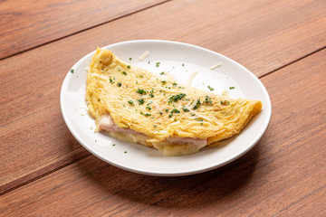 Omelet with parsley and cheese for breakfast on wooden background.