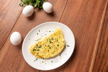 Omelet with parsley and cheese for breakfast on wooden background.